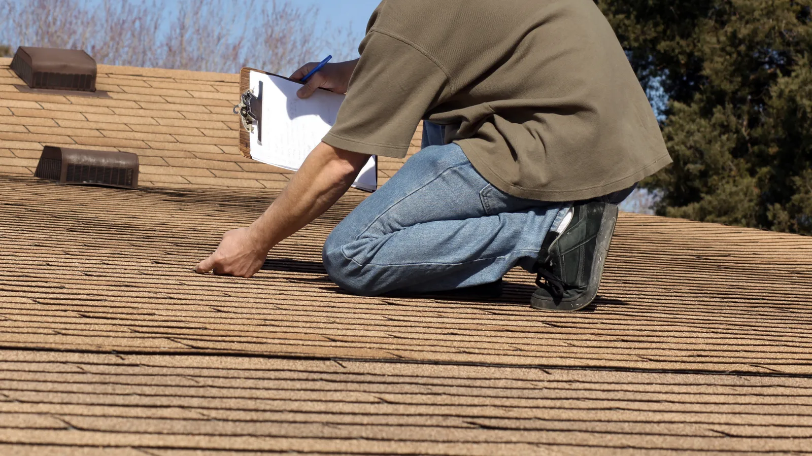 Shingles near roof vents checked by an inspector with a clipboard